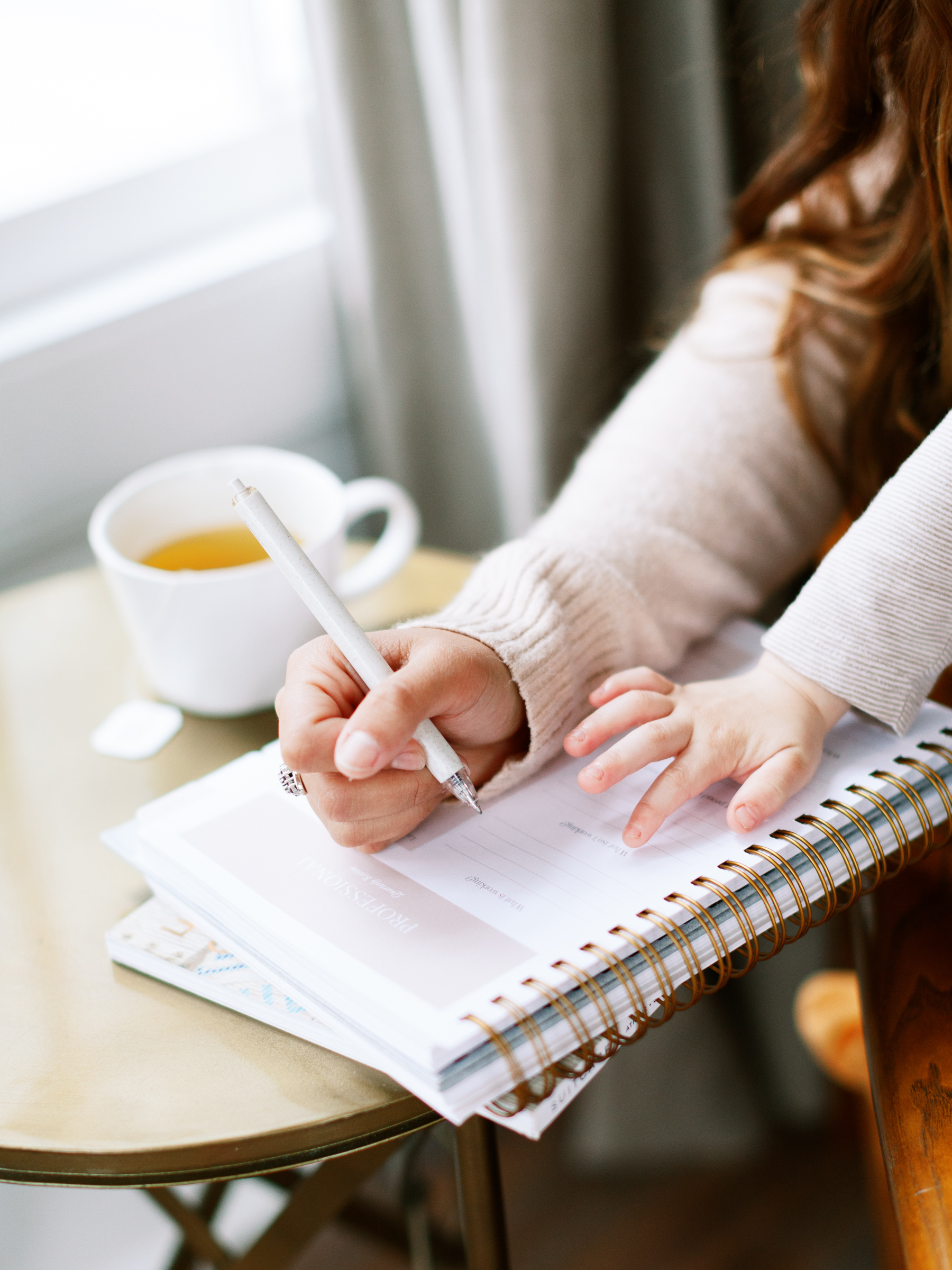 An image of a busy mom organizing her to-do list with a child sitting with her